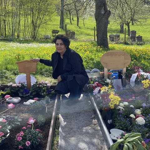 Meryem Üge-Evren kniet neben dem Grab ihres Mannes auf dem Friedhof in Nagold