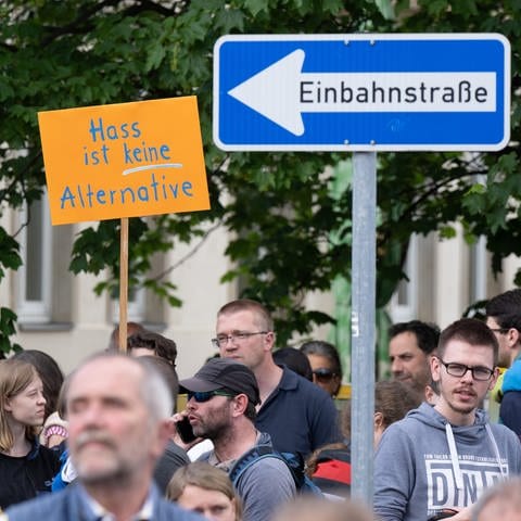 Teilnehmer einer Kundgebung stehen auf dem Pohlandplatz und halten ein Schild mit der Aufschrift „Hass ist keine Alternativ